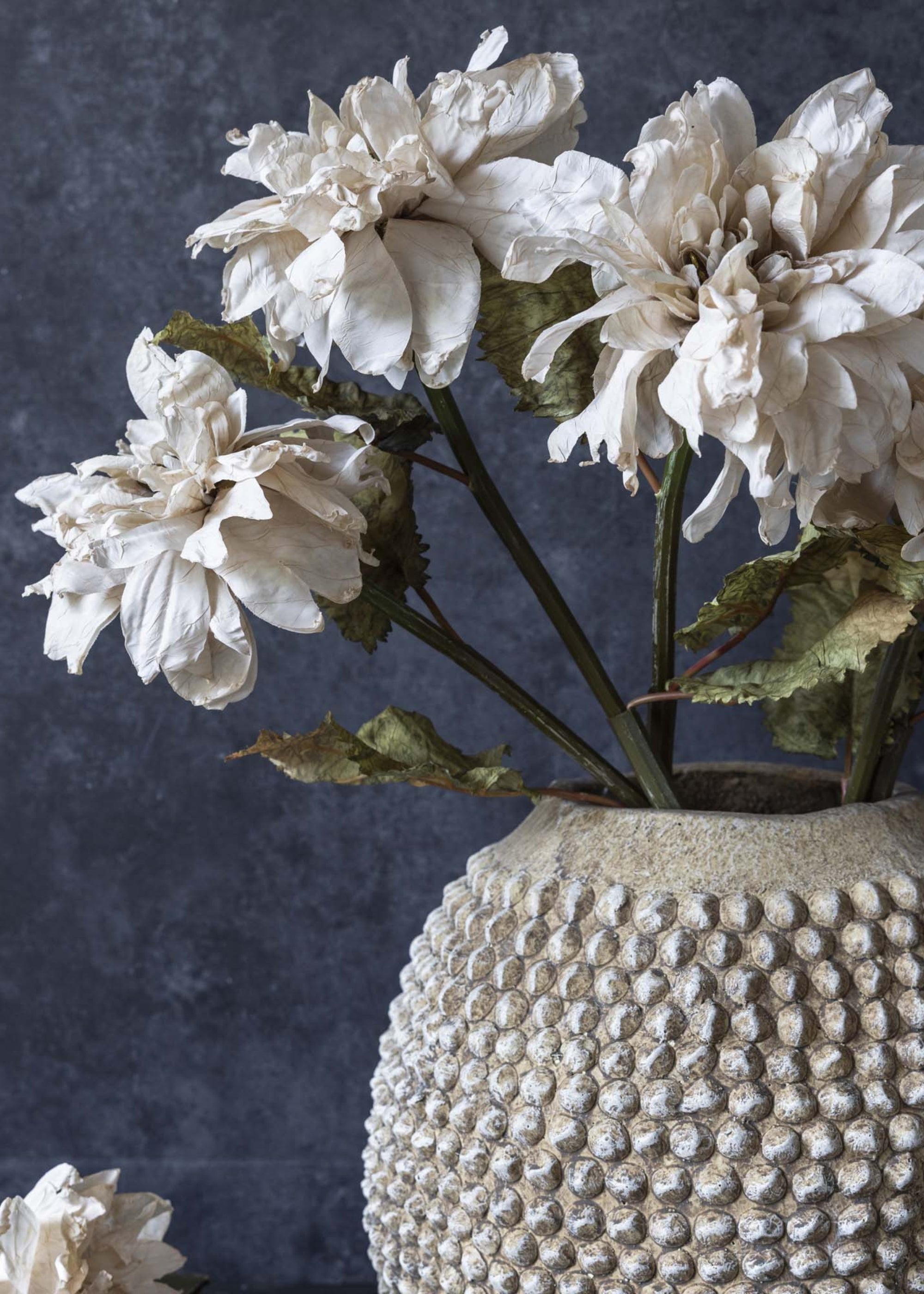 Neutral faux dahlia flower arranged with greenery in living room
