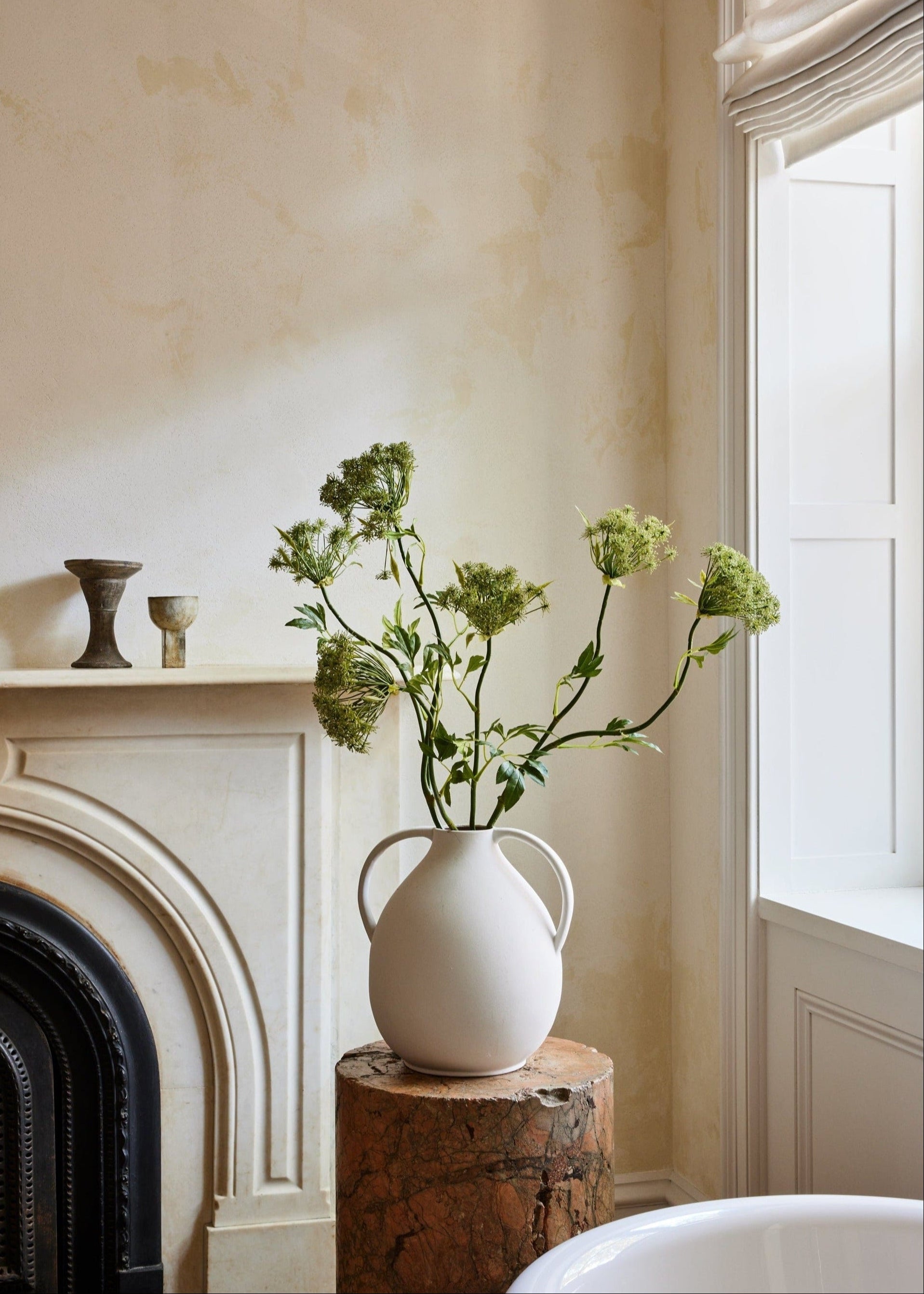 Clay jug vase styled with tall artificial branches